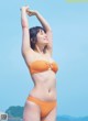 A woman in an orange bikini standing on a beach.