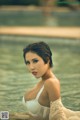 A woman in a white lingerie sitting in a pool.