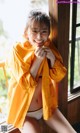 A woman in a yellow raincoat sitting on a window sill.