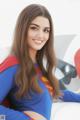 A woman in a superman costume sitting on a couch.