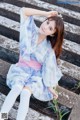 A woman in a blue and pink dress sitting on some steps.