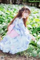 A woman in a blue and pink kimono sitting in a field of flowers.