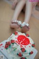 A woman sitting on the floor with her feet on a cake.