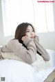 a woman laying on top of a bed next to a window