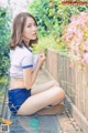 A woman sitting on the ground next to a wooden fence.