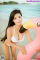 A woman in a white bikini holding a pink flamingo.