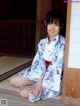 A woman in a blue and white kimono sitting on the floor.