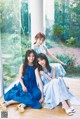 A group of three young women sitting on a wooden floor.