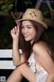 A woman in a straw hat sitting on a bench.