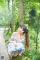 A woman in a blue and white dress sitting on a tree stump.