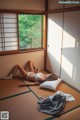 A woman laying on a bed in a room with a window.