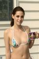 A woman in a bikini holding a cup of coffee.