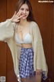A woman in a white bra top and plaid skirt posing for a picture.