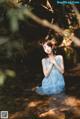 A woman in a blue dress is sitting in the water.