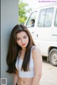 A woman leaning against a wall in front of a white van.