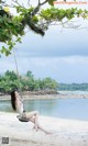 A woman sitting on a swing on a beach.