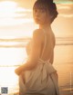 A woman in a white dress standing on a beach.