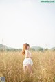 A woman in a white dress standing in a field.