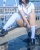 A woman in a school uniform sitting on a ledge.