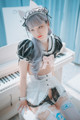 A woman in a maid outfit sitting on a piano.