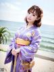 A woman in a purple kimono standing on a beach.