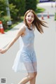 A young woman in a blue dress is walking down the street.