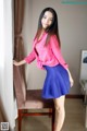 A woman in a pink shirt and blue skirt posing for a picture.