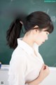 A woman in a white shirt standing in front of a blackboard.