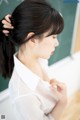 A woman with long black hair standing in front of a blackboard.