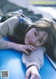 A young girl laying on top of a blue car.