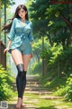 A woman in a blue romper and thigh high boots walking down a path.