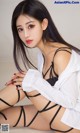 A woman in a white shirt and black lingerie sitting on a bed.